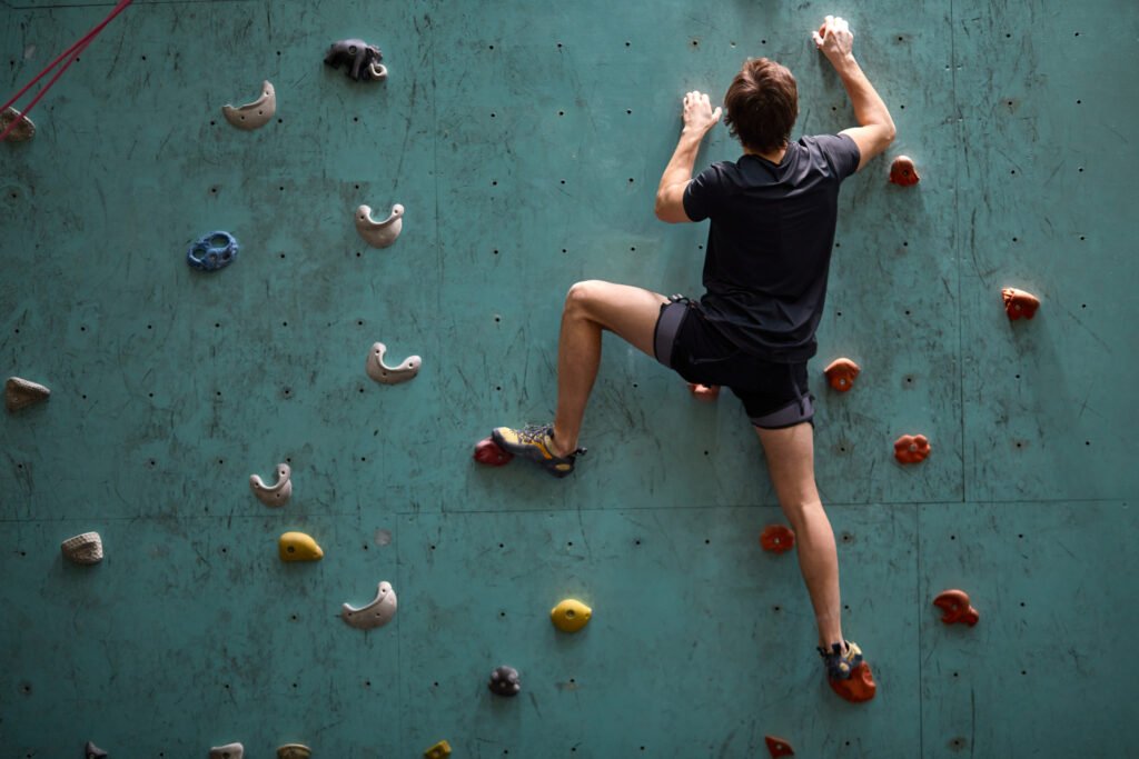 Strong anf git young caucasian man on rock wall in sport center, rock climbing